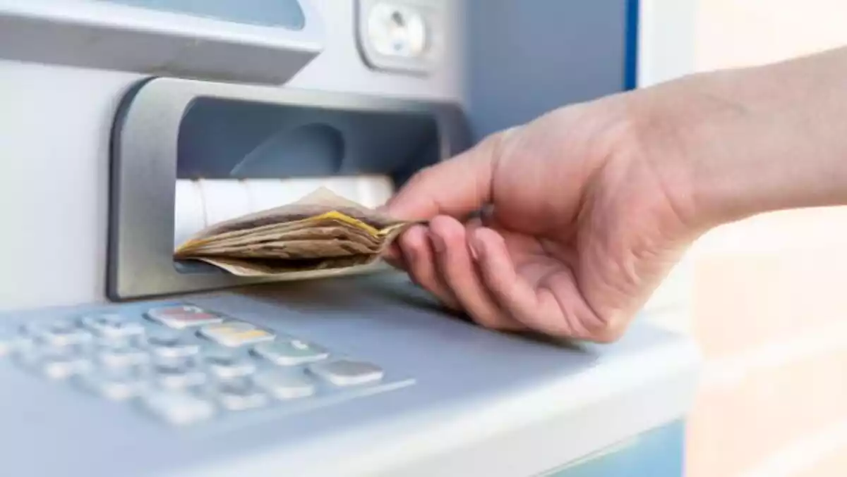 Mano de una persona sacando varios billetes de 50 euros de un cajero automático